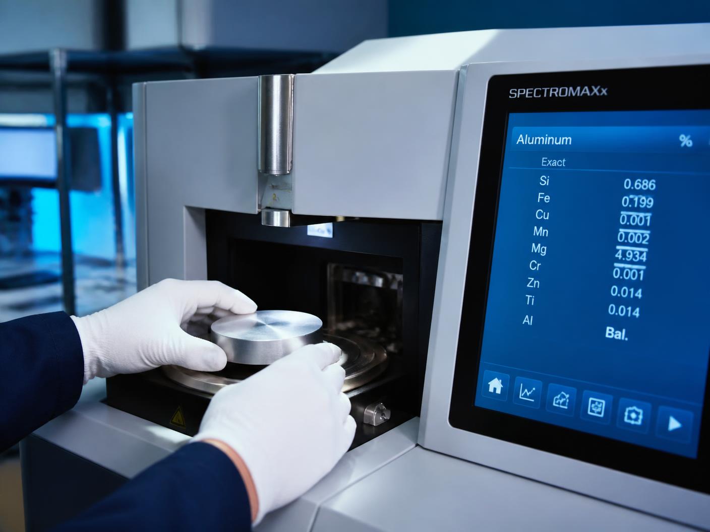 Technician loading an aluminium sample disc into an optical emission spectrometer